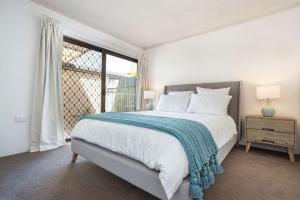 a white bedroom with a large bed and a window at River Front Escape, Walk to Ocean St & Shops in Maroochydore