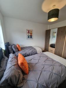 哈德斯菲爾德的住宿－Vibrant Modern Apartments，一间卧室配有两张带橙色枕头的床