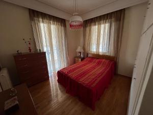Schlafzimmer mit einem roten Bett, einer Kommode und Fenstern in der Unterkunft Διαμερισμα 77τ.μ in Sparta