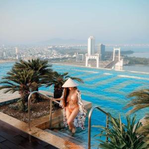 uma mulher de chapéu está ao lado de uma piscina em GOLDEN APARTMENT With SEA VIEW em Da Nang
