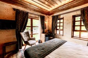 a bedroom with a bed and a chair and windows at Flavia Cappadocia Hotel in Uchisar