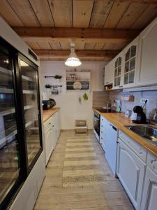 cocina con armarios blancos y techo de madera en DRiM Wood House, en Lasinja