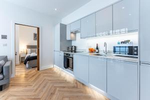 cocina con armarios blancos y suelo de madera en Wellington House by Celador Apartments en Reading