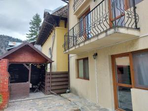 een geel huis met een balkon en een deur bij Vila Foc Alb Apartamente-Busteni in Buşteni