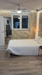 Un dormitorio con una cama blanca y una pared de piedra. en Apartamentos Marqués, en Alicante
