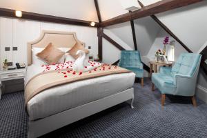 a bedroom with a bed and two blue chairs at WA Hotel (Wroxall Abbey) in Wroxall