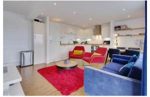 a living room with a blue couch and red chairs at Beach Penthouse Apartment Bournemouth in Bournemouth