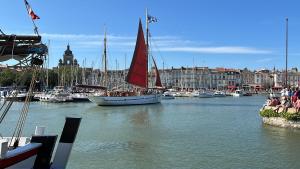 un barco con una vela roja en un puerto en Nid douillet T2 wifi centre historique 3 étoiles en La Rochelle