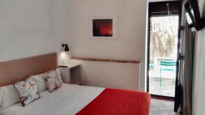 een slaapkamer met een bed met een rode deken en een raam bij Hostal Café FRENTEABASTOS in Carmona