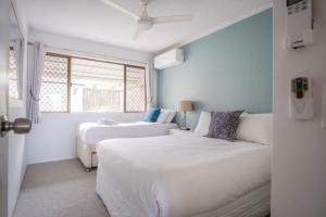 a white bedroom with two beds and a window at Peaceful River Front Escape Short walk to Ocean St in Maroochydore