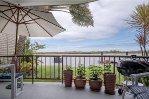 a grill on a balcony with a view of the water at Peaceful River Front Escape Short walk to Ocean St in Maroochydore