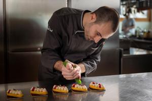 un hombre está preparando comida en una cocina en Sport Hotel Cristal, en Falcade