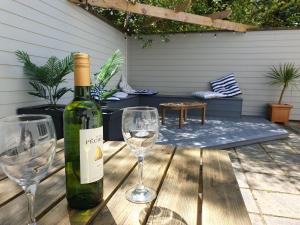 Una botella de vino y dos copas de vino en una mesa de madera. en Golygfa Mor Tresaith 