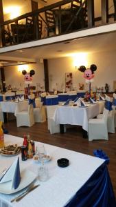 a dining room with white tables and chairs with pigs on the wall at Hamlet Hotel in Bacău