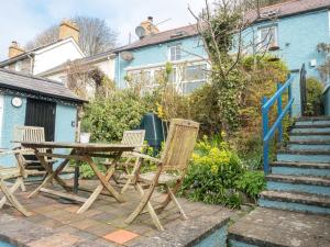 un patio con mesa y sillas frente a una casa en Driftwood Cottage Llangrannog en Llangranog