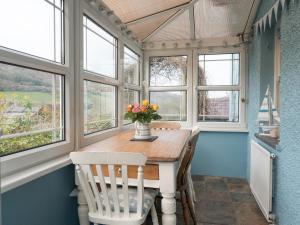 a dining room with a table and chairs and windows at Driftwood Cottage Llangrannog in Llangranog