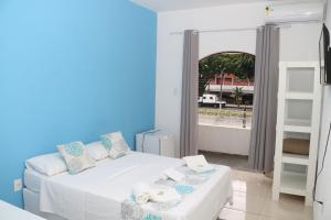 a blue and white bedroom with a bed and a window at Pousada Lisamar in Mangaratiba