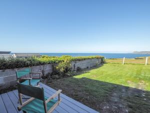 two chairs sitting on a wooden deck with the ocean in the background at Hiraul Aberporth in Aberporth