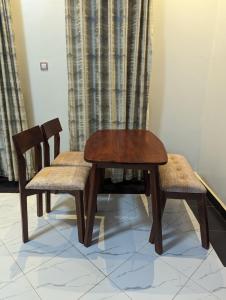 une table en bois et deux chaises assises à côté d'un rideau dans l'établissement La Dolce Vita, à Kampala