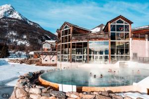 a building with a hot tub and a mountain at Le repaire du vieux cerf in Le Monêtier-les-Bains