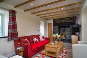 a living room with a red couch and a fireplace at Bwthyn Briallen Crymych in Crymmych Arms