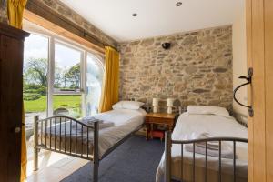 two beds in a room with a stone wall at The Grain Store Newgale in Llandeloy