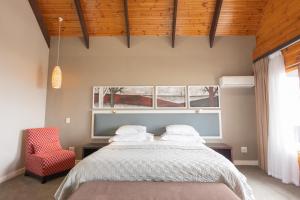 a bedroom with a bed and a red chair at The Kelway Hotel in Port Elizabeth