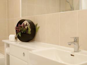 La salle de bains est pourvue d'un lavabo, d'un miroir et d'une plante. dans l'établissement London ExCeL Stays, à Londres