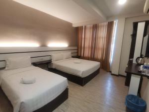 a hotel room with two beds and a window at Grand Kapar Hotel Kuala Selangor in Kuala Selangor