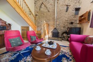 a living room with pink chairs and a fireplace at The Stables Newgale in Llandeloy