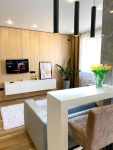 uma sala de estar com uma mesa branca e uma televisão em Apartament Almaty Akvarel em Almaty