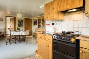 a kitchen with wooden cabinets and a stove at Cnwc Y Bran St Nicholas in Saint Nicholas