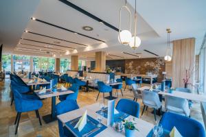 uma sala de jantar com mesas e cadeiras azuis em Sungarden Wellness & Family Hotel em Siófok