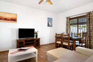 uma sala de estar com um sofá, uma televisão e uma mesa em Casa Ale em Cádiz