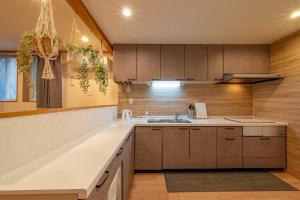 een keuken met houten kasten en een wastafel bij New Open 天神橋筋六丁目駅徒歩1分 バーカウンター付き一軒家 天満居酒屋街徒歩3分 梅田 難波10分 in Osaka