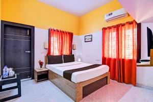 a bedroom with a bed with red curtains and a television at OYO Home Modern Stay Near Iter in Khandagiri