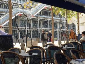 Charmant appartement en plein coeur du Marais في باريس: فناء في الهواء الطلق مع طاولات وكراسي ومبنى