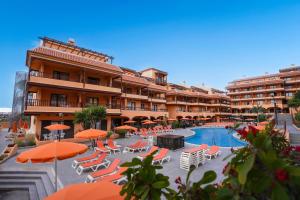 a hotel with a swimming pool and chairs and umbrellas at Coral Los Alisios in Los Cristianos