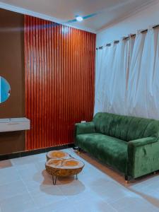 Dream Stay Lodge and Restaurant في دودوما: غرفة معيشة مع أريكة خضراء وطاولة