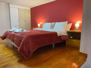 a bedroom with a large bed with a red wall at Μεζονέτα Τοξότης in Chios