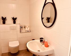 ein weißes Badezimmer mit einem Waschbecken und einem Spiegel in der Unterkunft Cologne Chic: Mexx Opulence Köln in Köln