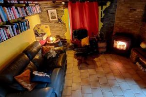 sala de estar con sofá de cuero y chimenea en L'Ardoisière: jolie maison ardennaise., en Alle