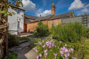 ein altes Backsteingebäude mit Blumen davor in der Unterkunft Rosemary Cottage in Leicester