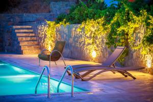 two chairs sitting next to a swimming pool at night at Pezoulia in Selakano