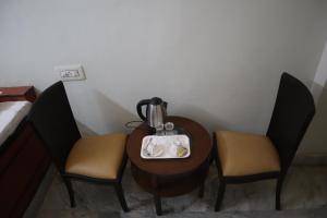 Habitación con mesa con 2 sillas y hervidor de agua. en SWET APARAJITA en Bolpur