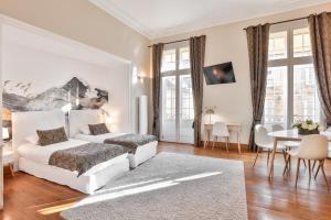 Dormitorio blanco con cama y mesa en La Villa des Consuls - Gîte de tourisme de charme en Sarlat-la-Canéda