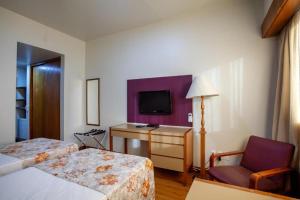 Cette chambre comprend deux lits, une chaise et une télévision. dans l'établissement Hotel Nacional Inn Belo Horizonte, à Belo Horizonte