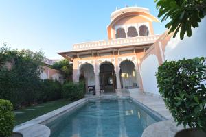 a house with a swimming pool in front of a building at Buena Vista Luxury Garden Spa Resort in Jaipur