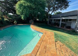 a swimming pool with a brick walkway next to a house at Lloyd Road Cottage in Hallack Rock