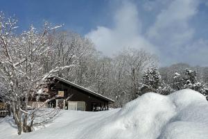 una pila de nieve frente a una cabaña en 1日1組の宿　OTTABIO（オタービオ） en Hirosaki